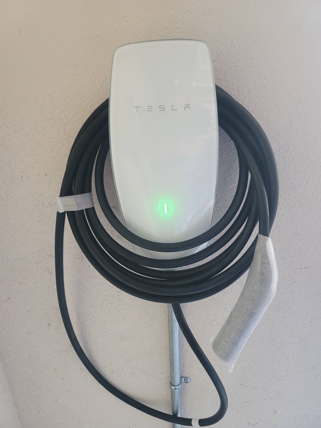 Tesla wall connector installed neatly with its charging cable coiled around the unit