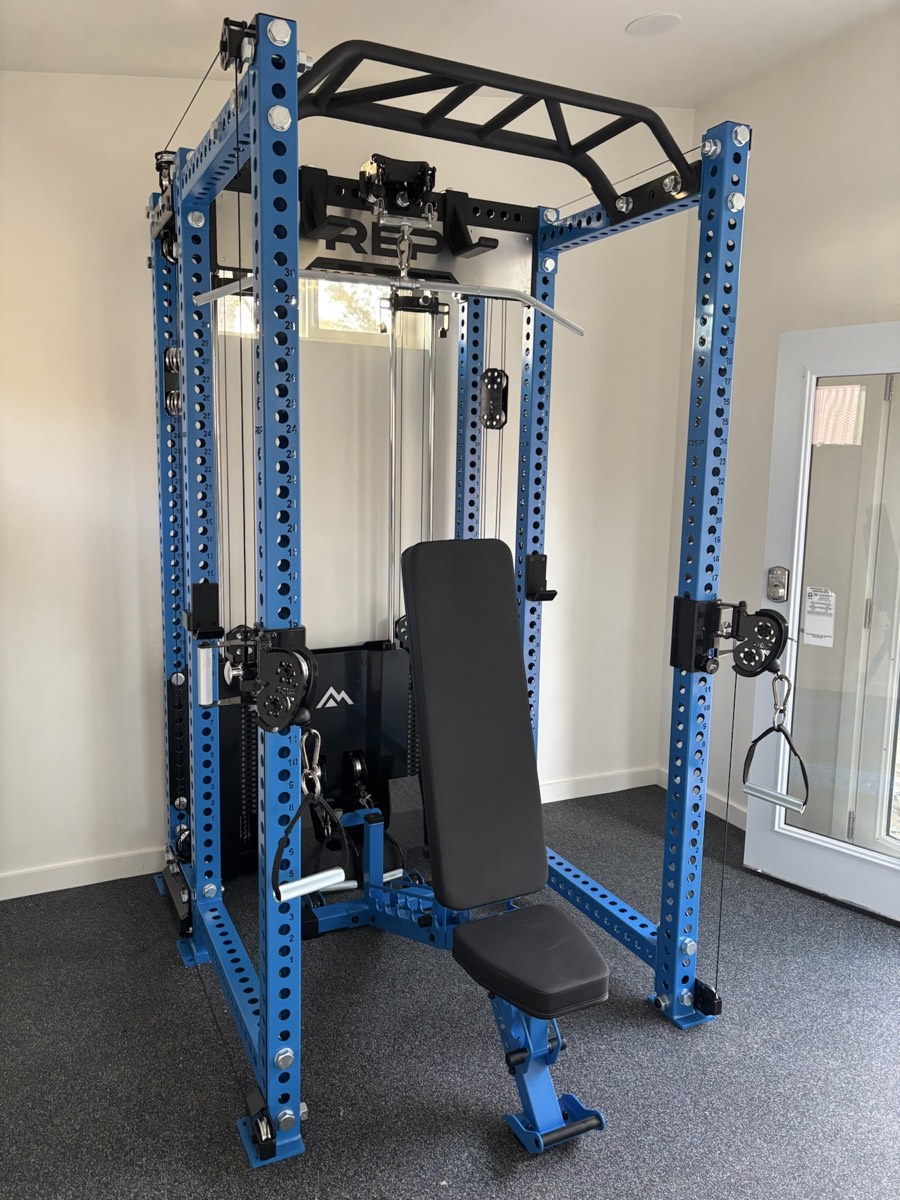 Blue REP fitness rack and cable system assembled in a finished home gym
