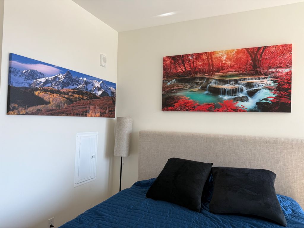 Two landscape canvases mounted above a bed