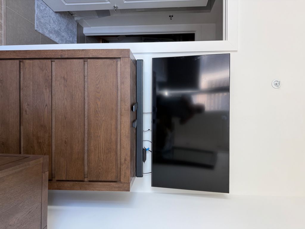 Wall-mounted flat-screen television beside a bedroom cabinet
