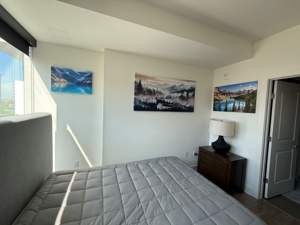 Three landscape canvases mounted across a bedroom wall