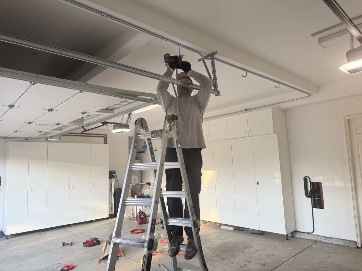 Alex_SD team member installing overhead electrical hardware in a garage